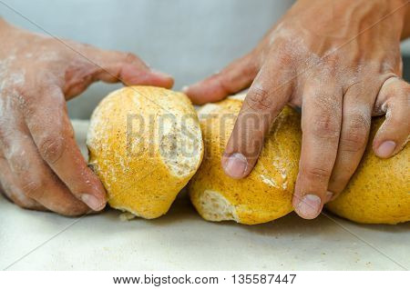 Bakers hands stacking fresh delicious buns of bread against each other.