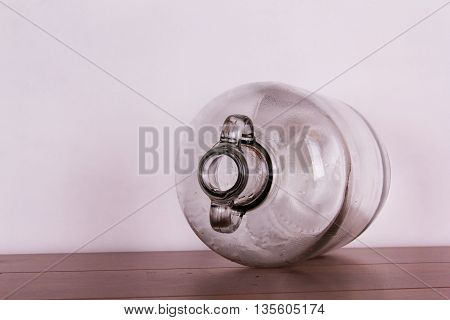Clear Glass Demijohn Against A Light Background