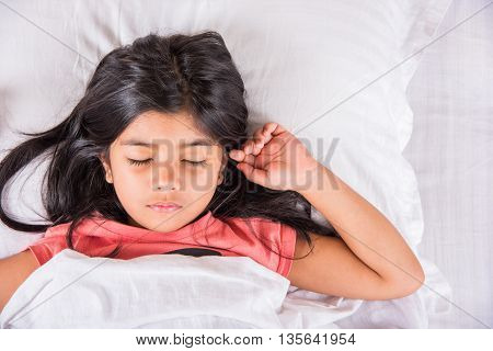 cute Indian Girl sleeping over white pillow, small asian girl sleeping on bed