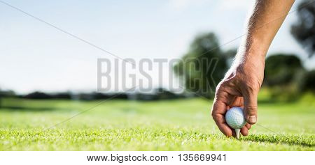 Golfer placing golf ball on tee on a sunny day at the golf course