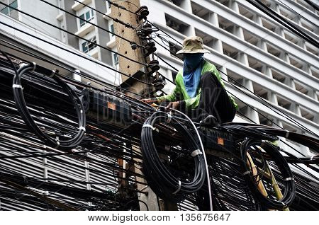 BANGKOK THAILAND - JUNE 18 2016: Unidentified worker works on the power line on the street Bangkok Thailand.