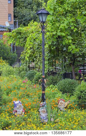 Example of garden decoration: street lamp and figurines of dwarf in garden decor