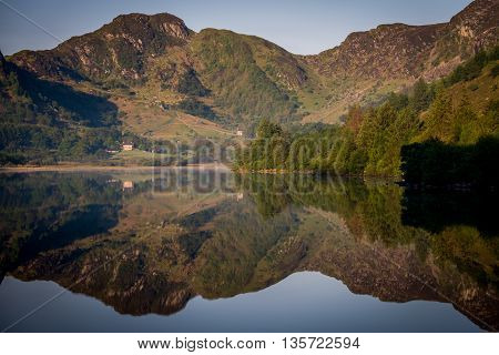Perfectly symmetric reflections on a mirror-like lake at sunrise