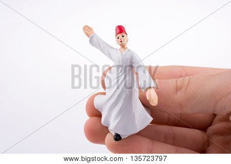 Hand holding a Sufi Derviş on a white background