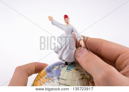 Hand holding a Sufi Derviş on a globe