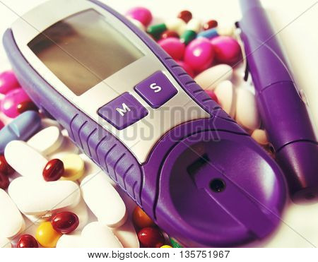 device for measuring blood sugar level isolated on white background and pills 