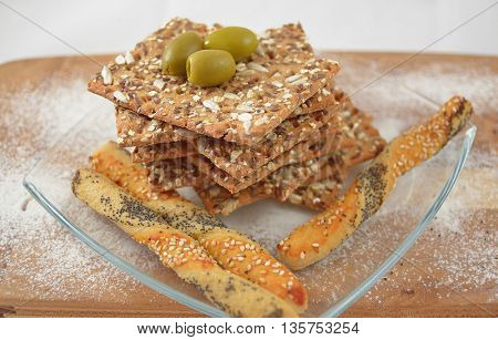 salty sticks with sesame and poppy seeds, Bread sticks or Pretzel sticks,linen tiles and olives