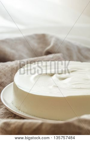 No-bake vanilla bavarian mousse cake with cream cheese, mascarpone and whipped cream. White plate. Free text space. Close up.