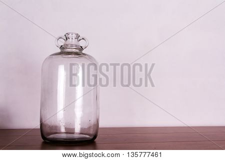 Clear Glass Demijohn Against A Light Background