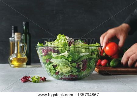 Full bowl of fresh salad closeup on a light table against a dark background. Concept helpful and simple food