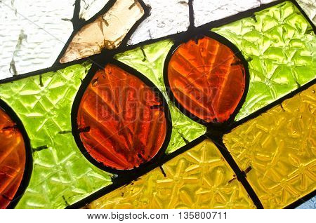 Red leaves in stained glass window. Abstract geometric colorful background. Multicolored stained glass church window with irregular random block pattern.