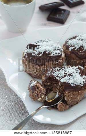 A photo of chocolate cakes on a white plate and a cup of coffee