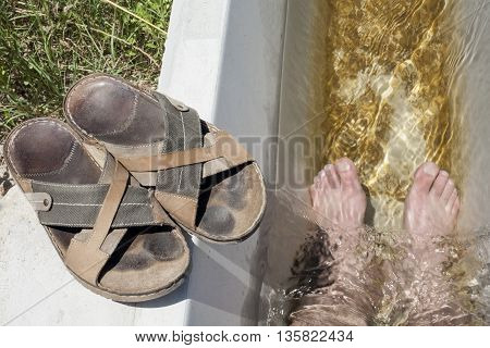 Man feet refreshing in a cool irrigation canal during the hottest day hours Vegas Altas del Guadiana Spain