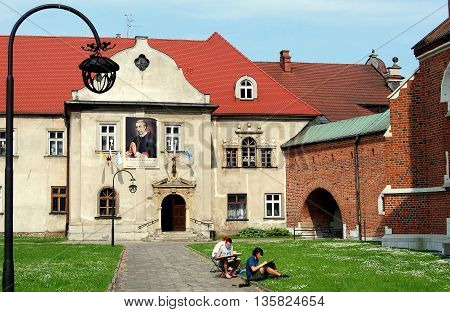 Krakow Poland - Jine 7 2010: Three university art students drawing in the courtyard of the Corpus Christi Church (right) with the Bishop's Palace behind them