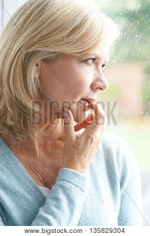 Sad Mature Woman Suffering From Agoraphobia Looking Out Of Window