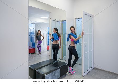 Alluring girls posing in locker room of fitness center