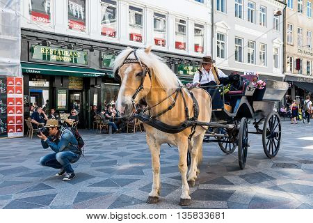 Strøget, Copenhagen City center on a sunny May day, with a fancy arriage taxi and a street photographer taking a shot