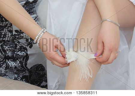 bridesmaid helping bride to put on garter bridesmaid dresses bride's garter