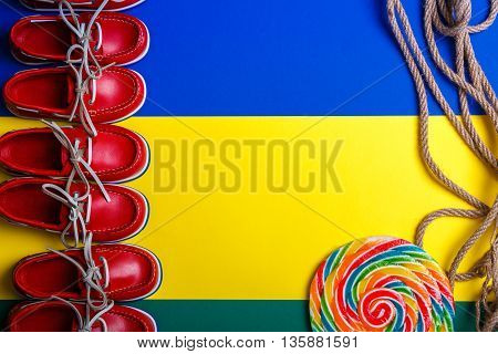 A lot of small red boat shoes near big multi-colored lollipop on colored background. Top view copy space. Frame. group of child boat shoes.
