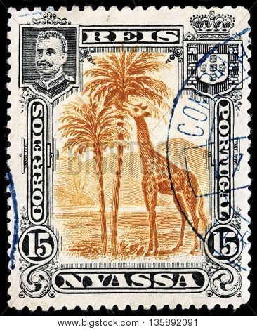 LUGA RUSSIA - JUNE 25 2016: A stamp printed by NYASSA shows image portrait of King Carlos I of Portugal against African landscape with giraffe. Niassa is a province of Mozambique circa 1901