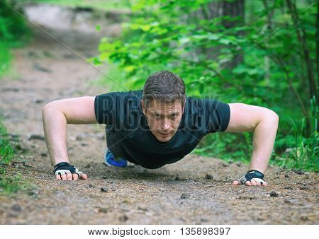Handsome Man Doing Push-ups In The Forest.