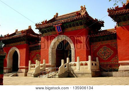 Beijing China - May 6 2005: Three gateways with rounded arches flanked by carved designs and tiled roofs with ceramic animal figures lead into the Heavenly King Hall Pavilion in Behei Park