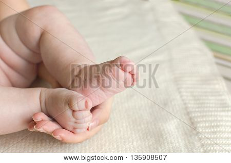 Baby feet in mother hands. Tiny Newborn Baby's feet on female Shaped hands closeup. Mom and her Child. Happy Family concept. Beautiful conceptual image of Maternity