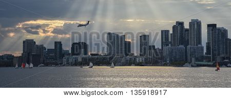 TORONTO SKYLINE WITH AIRPLANE AND SUNBEAMS IN THE DISTANCE