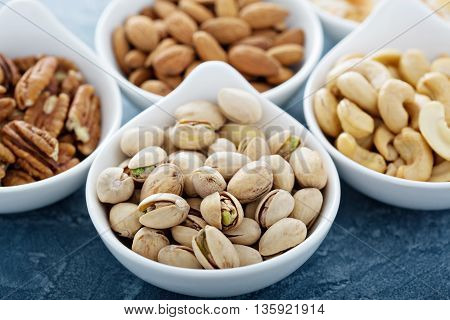 Variety of nuts in small white bowls healthy snacks