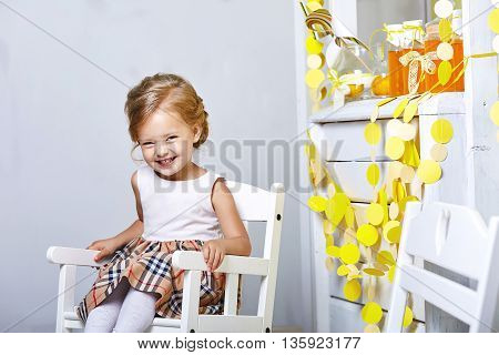 Beautiful little girl.Blue-eyed blonde.White chair.Lemonade.Children's room. Happy small girl portrait.