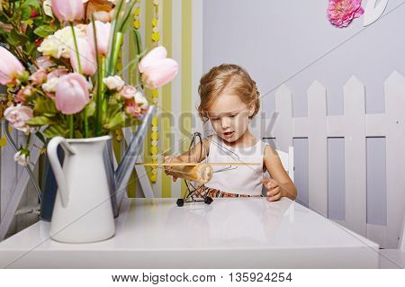 Beautiful little girl playing toys.Blue-eyed blonde.White chair.Children's room. Happy small girl portrait.