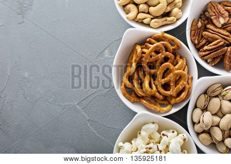 Variety of healthy snacks in white bowls pretzels and nuts