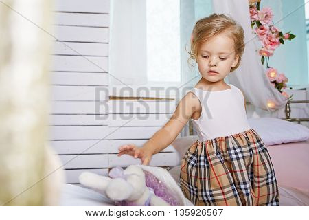 Beautiful little girl playing with soft rabbit.Blue-eyed blonde.Children's room. Happy small girl portrait.