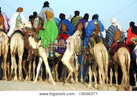 Uomo cavallo dietro un gruppo di Tuareg su cammelli