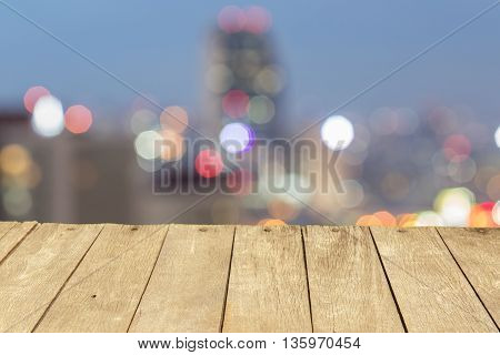 Empty wooden table or plank with bokeh of light from city tower on background for product display.