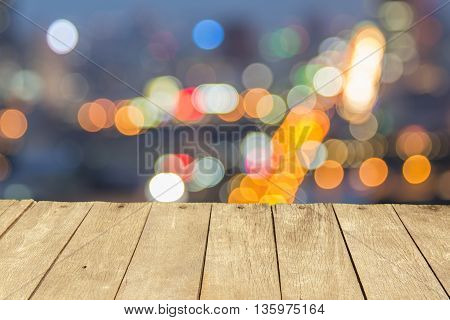 Empty wooden table or plank with bokeh of light from city tower on background for product display.