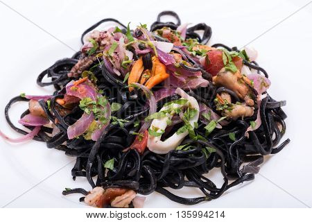 Black spaghetti with seafood and vegetables in white plate