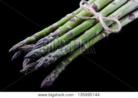 Raw asparagus on black background