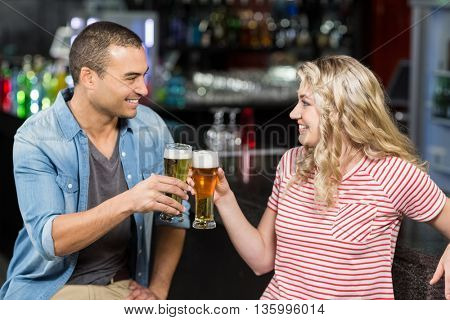 Cute couple toasting with beers in a pub