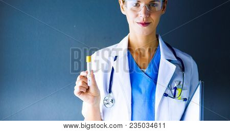 Female medical or research scientist or doctor using looking at a test tube of clear solution in a lab or laboratory.