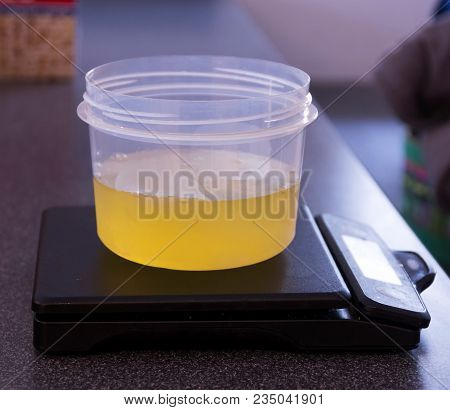 Egg Ehites In A Plastic Container Are Being Weighed On Black Digital Scale.