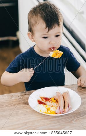 A Child In The Kitchen Eats Eggs Or Omelets In The Afternoon
