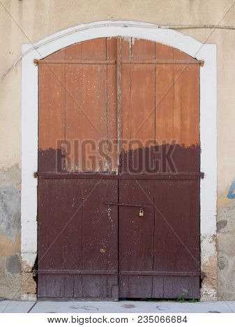 Old Picturesque Decaying Half Brown Painted Wooden Double Doors Bolted Shut With A Padlock Set In A 