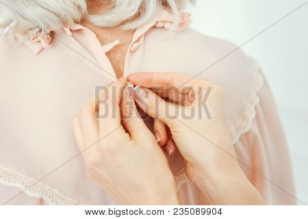 Only Few Left. Scaled Up Look On Hands Of Thoughtful Young Woman Doing Up All The Buttons On A Peach