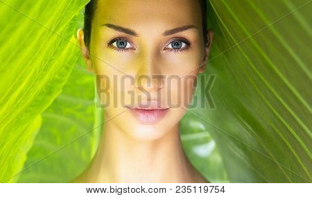 Beautiful Woman Face With Natural Nude Make-up On A Tropical Leaf Background. Healthy Life. Sexy Bea