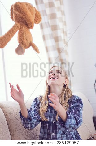 We Are Happy To Regain Our Childhood. Happy Teenage Girl Playing With Teddy Bear Sitting On Sofa. We