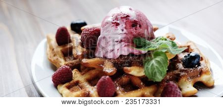 Plate of belgian waffles with ice cream and fresh berries - raspberries and blueberries. top view