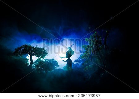 Horror Halloween Decorated Conceptual Image. Alone Girl With The Light In The Forest At Night. Silho