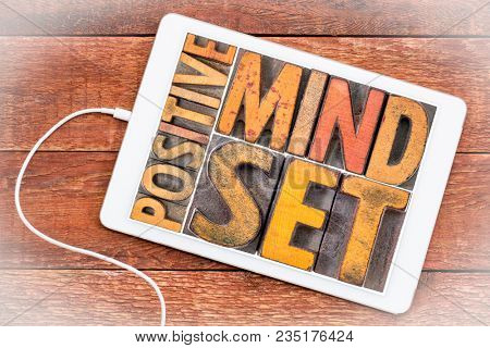positive mindset word abstract in vintage letterpress wood type on a digital tablet