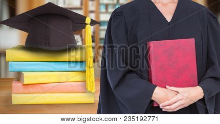 Mid section of female graduate holding red diary while standing by mortar board and stack of books